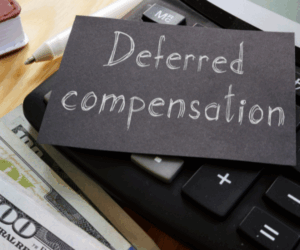 calculator with a piece of paper on top that says deferred compensation