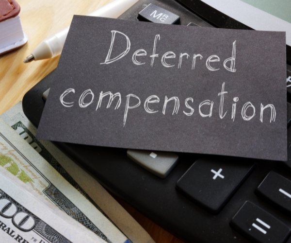 calculator with a piece of paper on top that says deferred compensation